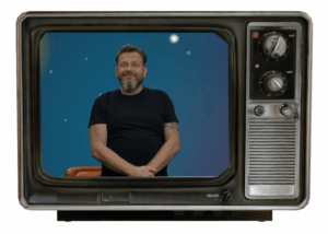 Ein Fernseher, wo man eine Personen sieht: Andreas. Er lächelt.